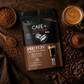 Bolsa de Café + Proteína y Cacao de Earth Co rodeada de granos de café y cacao, con una taza de café mocha.